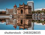 Iconic Gateway of India in Mumbai, Reflected Perfectly in Water, with a Flock of Birds Soaring Overhead and the Taj Mahal Palace Hotel in the Background