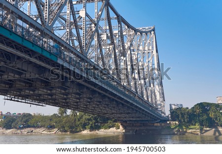 Iconic Howrah Bridge (Rabindra Setu) of Kolkata over Ganges river. Low angle view of one of the bridge anchorage from a ferry vessel crossing the river. The bridge is regarded as Gateway to Kolkata. 