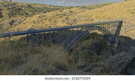 Iconic iron arch bridge of Requejo over Douro River, scenic view with moving plants and a white car crossing. - Powered by Shutterstock