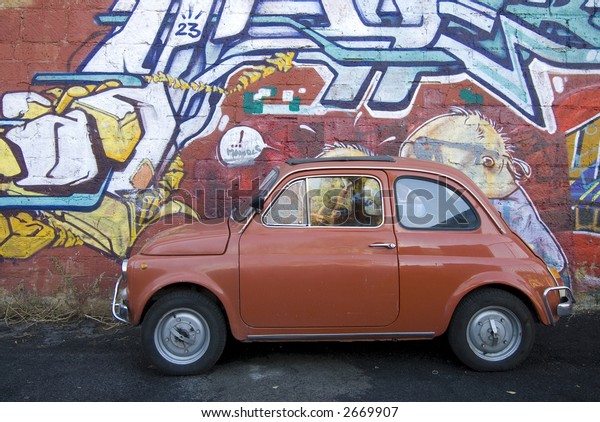 iconic italian small red car against contemporary\
graffiti background rome\
italy