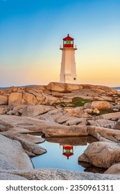 The iconic lighthouse at Peggy's Cove, Nova Scotia reflecting in a pool of water in early morning light