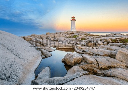 The iconic lighthouse at Peggy's Cove, Nova Scotia reflecting in a pool of water in early morning light