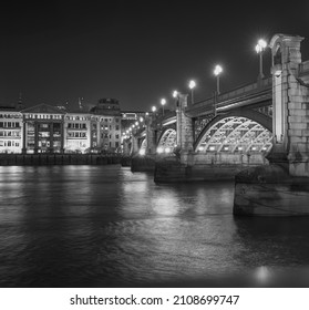 The iconic London Bridge lit up at night time, black and white