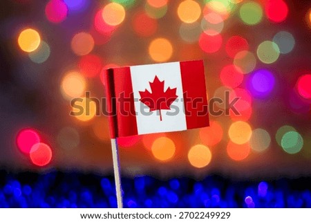 Canada’s iconic maple leaf flag set before colorful soft bokeh lights, expressing national pride, joyful holiday themes, and the warm spirit of Canadian celebrations.