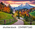 Iconic picture of Bavaria with Maria Gern church with Hochkalter peak on background. Fantastic autumn sunrise in Alps. Superb evening landscape of Germany countryside. Traveling concept background.
