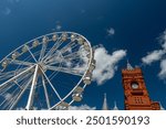  Iconic Pierhead Building in Cardiff Bay, Wales, with a Ferris wheel against a clear blue sky. Historic architecture meets modern attractions.