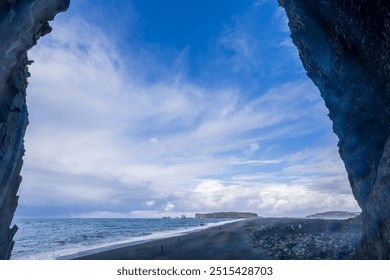 The iconic Reynisdrangar sea stacks rise dramatically from the black sand beach of Reynisfjara in Vik, Iceland. These basalt columns contrast sharply with the turbulent ocean and the rugged cliffs. - Powered by Shutterstock