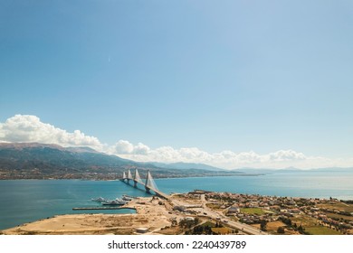 The iconic Rio Antirrio Bridge in Patras, Greece. The roadway of the Rio Antirrio Bridge is suspended from cables, giving drivers a stunning view of the surrounding landscape as they cross over water