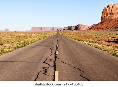 Iconic view of a long, straight road stretching into the distance through the desert landscape, flanked by majestic red rock formations under a clear blue sky. - Powered by Shutterstock