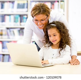 ICT Teacher With A Young Student Using The Computer