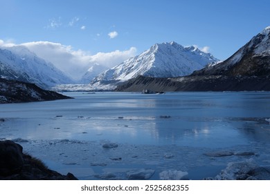 An icy glacial lake with floating icebergs surrounded by towering snowy mountains in New Zealand. The cold blue waters contrast beautifully with the rugged, snow-covered peaks. - Powered by Shutterstock