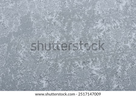 The icy surface of a window pane features stunning ice crystals, creating intricate patterns that resemble delicate lace. This image highlights the enchanting beauty of winters frost.