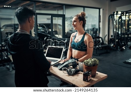Id like to sign up for premium membership please. Cropped shot of an attractive young sportswoman talking to a male fitness instructor at the reception of a gym.
