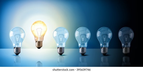 Idea concept with light bulbs sequence on a glass table with a lighted bulb on a blue background. Horizontal composition Front view - Shutterstock ID 395639746