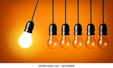 Idea Concept On Orange Background. Perpetual Motion With Light Bulbs