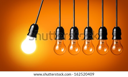 Idea concept on orange background. Perpetual motion with light bulbs