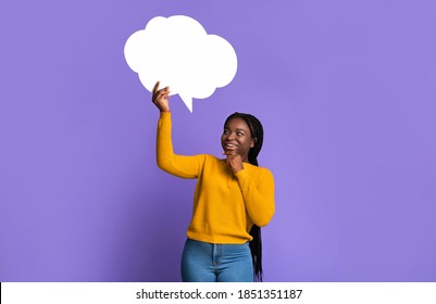 Idea Concept. Pensive Black Lady Holding And Looking Up At Blank Speech Bubble With Copy Space For Your Text Or Design, Curious African American Woman Posing Over Purple Studio Background