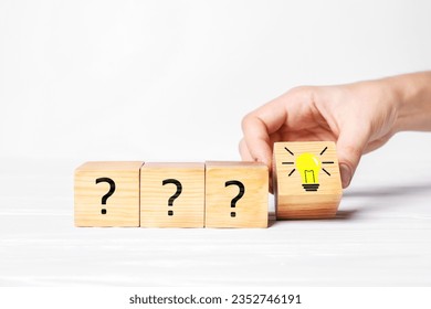 Idea concept. Woman putting cube with illustration of light bulb to other ones with question marks on white wooden table, closeup - Powered by Shutterstock