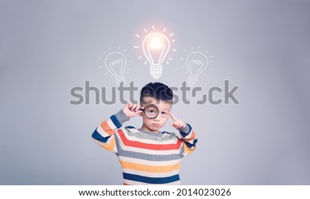 idea and creative concept. Cheerful boy with magnifying glass looking at on, thinking about something, learning concept, search, observation, Looking for answers.