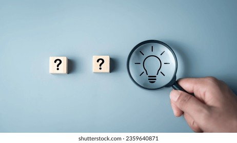 Idea creative thinks form  problem solving question concept. Magnifying glass focus on light bulb icon and  questions mark icon on wooden cube development inspiration discovery solutions to issues.