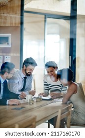 Idea People At Work. Through The Glass Shot Of A Group Of Colleagues Working Together In An Office.