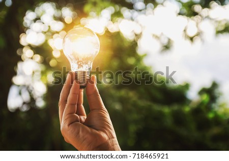 idea solar energy in nature, hand holding light bulb concept