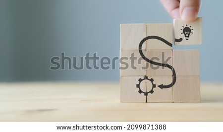 Idea and solution concept.Creative and innovation inspiration. Brainstorming to improve and develop the performance. Hand puts wooden cubes with idea and execution icon on grey background , copy space