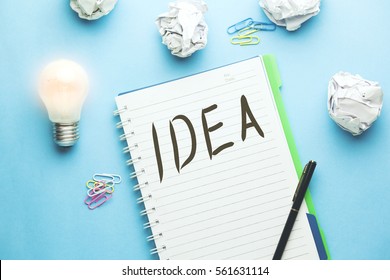 Idea text writeen on notebook with papers   and light bulb