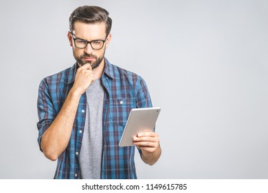 Idea! Thinking young man in plaid shirt standing and using tablet over grey background. - Powered by Shutterstock