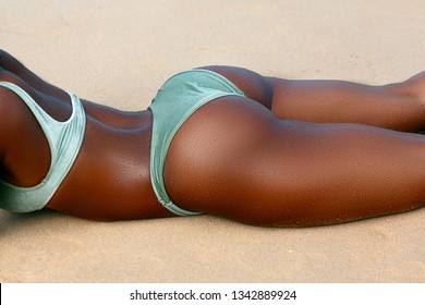 Ideal black african woman's butt and hips - perfect anti-cellulite and skin care therapy program. Ocean beach photo.