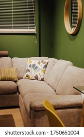 Ideal Home Show June 2019. Cropped Shot Of Couch With Pillows In Living Room With Green Wall.