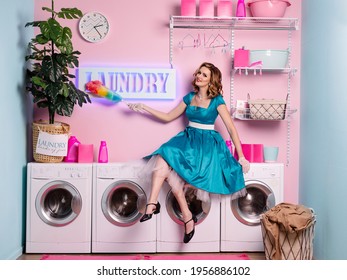 The Ideal Wife Is Both Caricature And Exaggeration. Beautiful Happy Housewife Wipes The Dust. Woman In Retro 60s Pin-up Style In The Laundry. Home Wash. Housekeeper At Work. Pink And Blue. Like A Doll