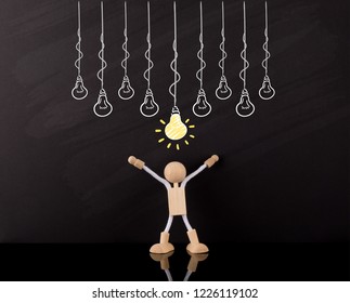 Ideas Concept, Wooden Stick Figure Arms Up, Big Yellow Light Bulb Sketch, Many Light Bulbs, On A Chalkboard, Brainstorming.