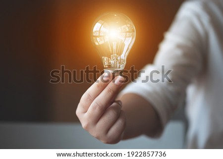 ideas creativity concept, woman holding light bulb in office.