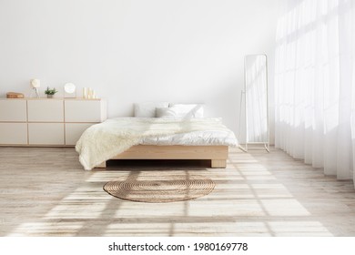 Ideas For Home Design, Minimalism And Morning Interior. Bed With Pillows, Soft Blanket, Carpet, Mirror, Furniture On Wooden Floor. White Wall, Large Window With Curtains In Bedroom, Nobody, Free Space