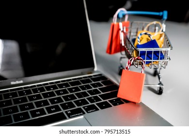 Ideas shopping onlice concept : Colorful paper shopping bag in trolley on laptop. Customer can buy everthing from office or home and the messenger will deliver.