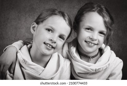 Identical Twin Girls Hugging In Studio