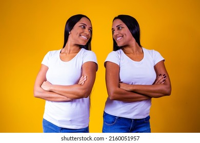 Identical Twin Sisters On Yellow Background With Arms Crossed