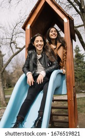 Identical Twins Having Fun On Slide In Playground