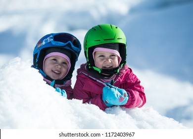 Identical Twins Are Having Fun In Snow. Kids With Safety Helmet. Winter Sport For Family. Little Kids Outside, Swiss Alps, Mountains, Healthy Lifestyle, Cheerful Family, Smiling Cute Girls