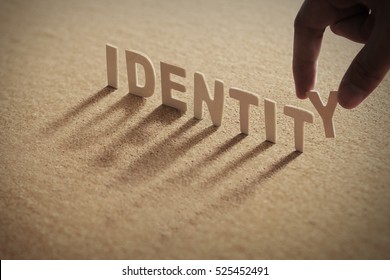 IDENTITY wood word on compressed board with human's finger at Y letter - Shutterstock ID 525452491