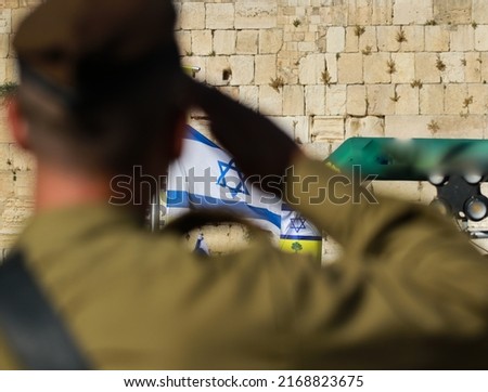 an IDF officer in front of the Israeli flag, the western wall