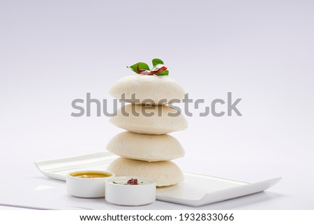 Idly or Idli, south indian main breakfast item which is beautifully arranged in a white plate on white background.