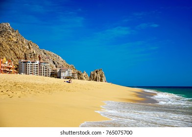 Idyllic Beach Scene, Golden Sands, Rocky Mountain Backdrop, Turquoise Sea And Deep Blue Sky. Bathers Relaxing On Pedregal Beach, Cabo San Lucas, Mexico