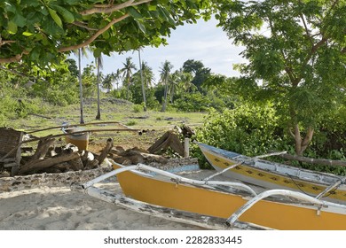 An idyllic clearing enclosed by trees on the beach of Pamilacan Island in the Philippines with a wooden boat. - Shutterstock ID 2282833445