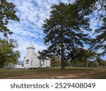 Idyllic country church and cemetery with tall trees in rural St Maurice, Louisiana. 