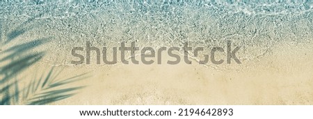 idyllic empty sand beach with water wave and palm leaf shadow from above, sunny summer vacation background with copy space for text or product presentation