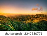 An idyllic landscape featuring a beautiful sunset over a mountain range, with lush grass and vibrant colors, Guam