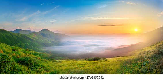 Idyllic landscape with green grass covered morning mountains with distant peaks and wide valley full of thick white cloudy fog. - Powered by Shutterstock