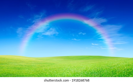 Idyllic landscape, rainbow over rolling green fields, in the background blue sky and white clouds - Powered by Shutterstock